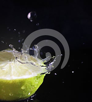 Water splashing over half a lime. Black background.