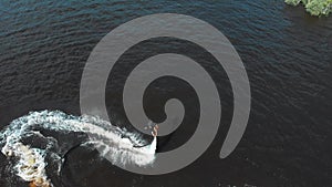 Water sports - a man flying around over the water on the flyboard in circles with a jet ski on the leash - aerial view