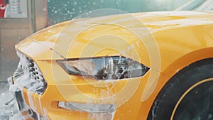 Water spray for car washing and cleaning. Washing his luxury yellow vehicle with high pressure water pump at automobile