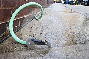 Water Spray gardening hose Nozzles lose up low angle with green hose going in the distance urban sidewalk