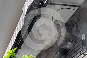 Water spray system and fans working for cooling air in street cafe on hot sunny summer day