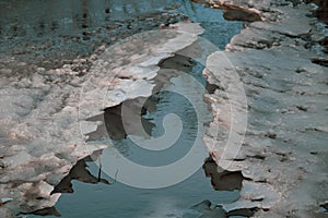 The water stream erodes ice in the spring