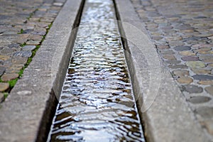 Water stream in formalised rill in pavement photo