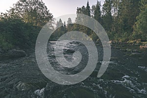 water stream in river of Amata in Latvia with sandstone cliffs, green foliage - vintage retro film look