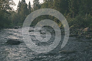 water stream in river of Amata in Latvia with sandstone cliffs, green foliage - vintage retro film look