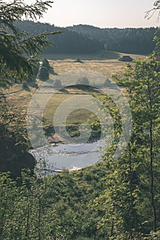 water stream in river of Amata in Latvia with sandstone cliffs, green foliage - vintage retro film look