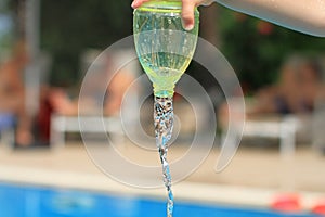 Water streaming from bottle held by hand of child