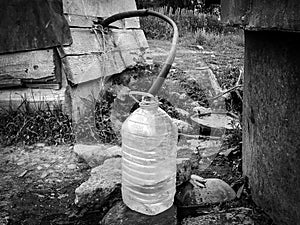 Water supply shortage and climate change threats: collecting drinking water with 5 liter plastic water bottle from a well in a rur