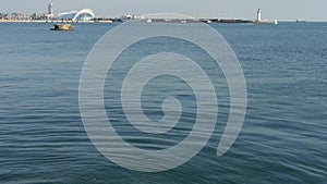 Water surface.Sailboat sailing in sea,relying on lighthouse dam at dusk.