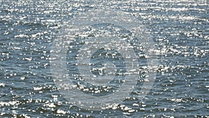 Water surface with waves glittering and shimmering in sun.