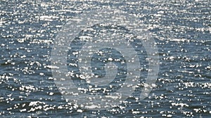 Water surface with waves glittering and shimmering in sun.