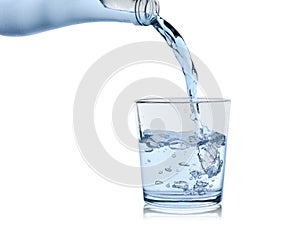 Water from the sweating bottle is poured in a glass glass, isolated on a white background