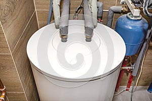 Water tank for a modern gas boiler in the home boiler room lined with ceramic tiles.