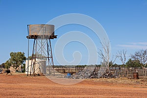 Water tanks, a wood pile and paddocks in a farm yard in Outback country, Australia.