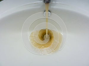 Water tap with running dirty muddy water in a sink