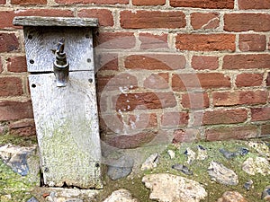 Water tap in wooden box secured into a stone and concrete footpath