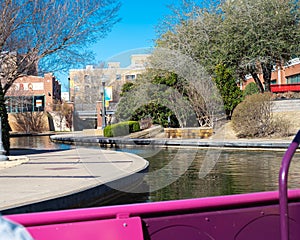 Water taxi cruises along canal with riverside buildings, hotels, restaurants in Bricktown, Entertainment District, Oklahoma City, photo