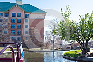 Water taxi cruises along canal with riverside buildings, hotels, restaurants in Bricktown, Entertainment District, Oklahoma City, photo