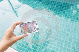 Water testing test kit in girl hand over blurred blue swimming pool water background