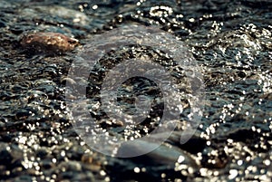 Water texture background. Sea water fast flow in the stones. Nature closeup