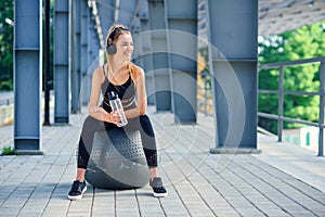 Water time. Woman leading healthy lifestyle drinking water before exercising on fitness ball