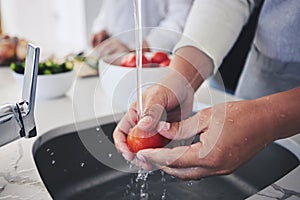 Water, tomato and hands cleaning vegetable for cooking in a kitchen basin or sink in a home for hygiene as a chef. Salad