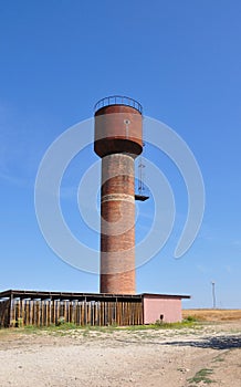 Water tower made of red bricks on blue sky background