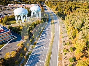 water tower near the road in a small town in the USA. Drone view. Autumn Forest, road, low-rise buildings