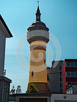 water tower with an old construction, on a clear sky with a yellow column photo