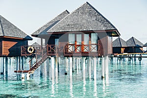 Water villas in Maldives in a sunny day, island paradise relax