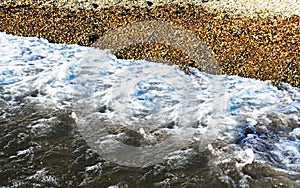 Water wave with pebble ashore