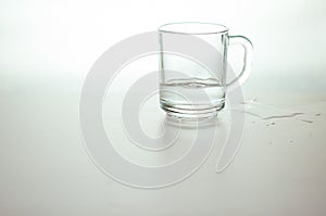 Water wave in transparent glass and puddle on gray background. purified drink water on table