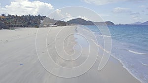 Water waves blue sea on sandy beach view from above. Sea waves splashing on sandy beach on tropical island on mountain