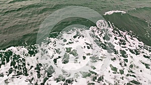 Water waves created by the moving ferry boat on the river. Side view near ship with white foam