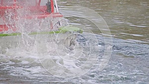 Water wheel on a historic steamboat traveling and smoking on a river