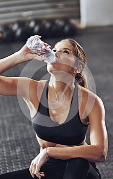 Water, woman and drink on floor, tired and rest in gym for exercise. Sweat, fatigue and sports centre for health and