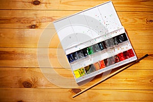 Watercolor aquarell paints in box with brush on wooden background