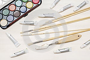 Watercolor oil tubes paints, paintbrushes, palette knife, colorful. Creativity creation process. Artist's stuff on
