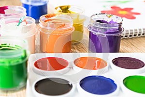 Watercolor paints and gouache in a jar on the table. Set for drawing, creativity and hobbies