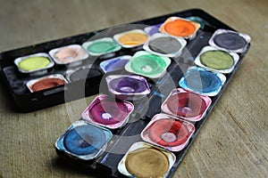 watercolor paints palette on a wooden table