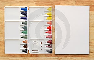 Watercolor paints set in white palette with white paper background
