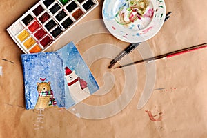 Watercolour seasonal greetings postcards on a table with palette and brushes