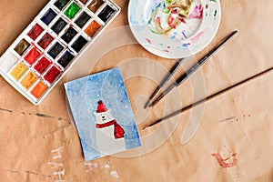 Watercolour seasonal greetings postcards on a table with palette and brushes