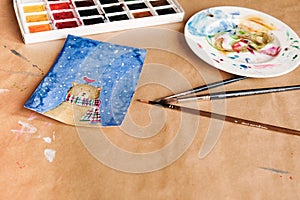 Watercolour seasonal greetings postcards on a table with palette and brushes