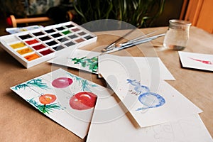 Watercolour seasonal greetings postcards on a table with palette and brushes