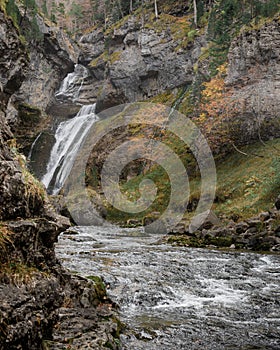 A waterfall in an autumn valley. Golden leaves and silky waters