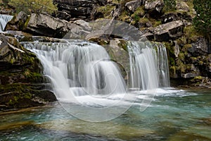 A waterfall in an autumn valley. Golden leaves and silky waters