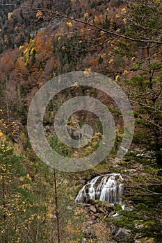 A waterfall in an autumn valley. Golden leaves and silky waters