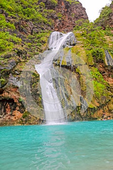 Waterfall in Ayn Khor and Lush green landscape, trees and foggy mountains at tourist resort, Salalah, Oman photo