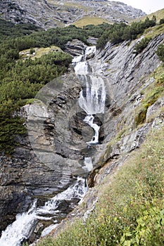 Waterfall below the summit of a mountain road Stelvio, Italy